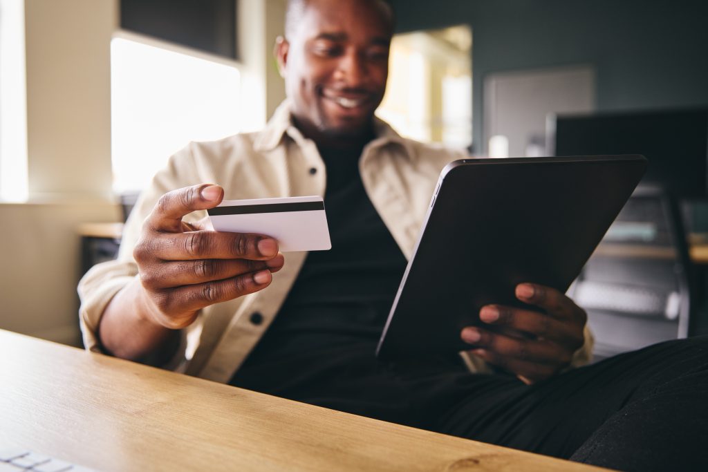 Man making online payment on tablet computer focused on credit card